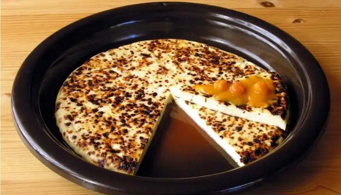A piece of golden-brown grilled Leipäjuusto cheese on a small plate next to a cup of coffee.
