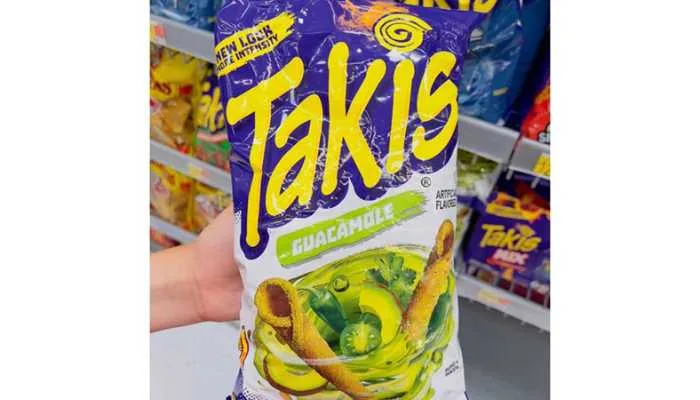 A colorful bag of Mexican Takis guacamole-flavored corn snacks resting on a wooden table.