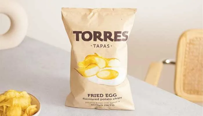 A gourmet black bag of Torres fried egg-flavored potato chips poured into a small bowl.